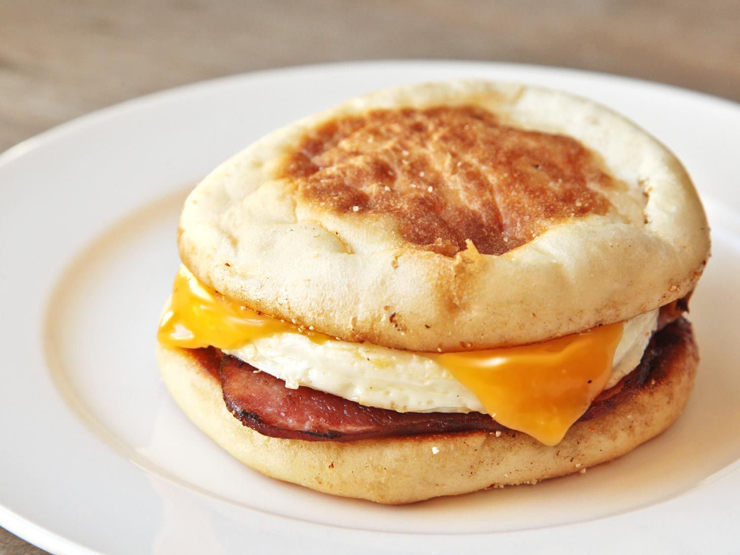 A classic breakfast sandwich with an egg, melted cheese, and bacon on an English muffin.