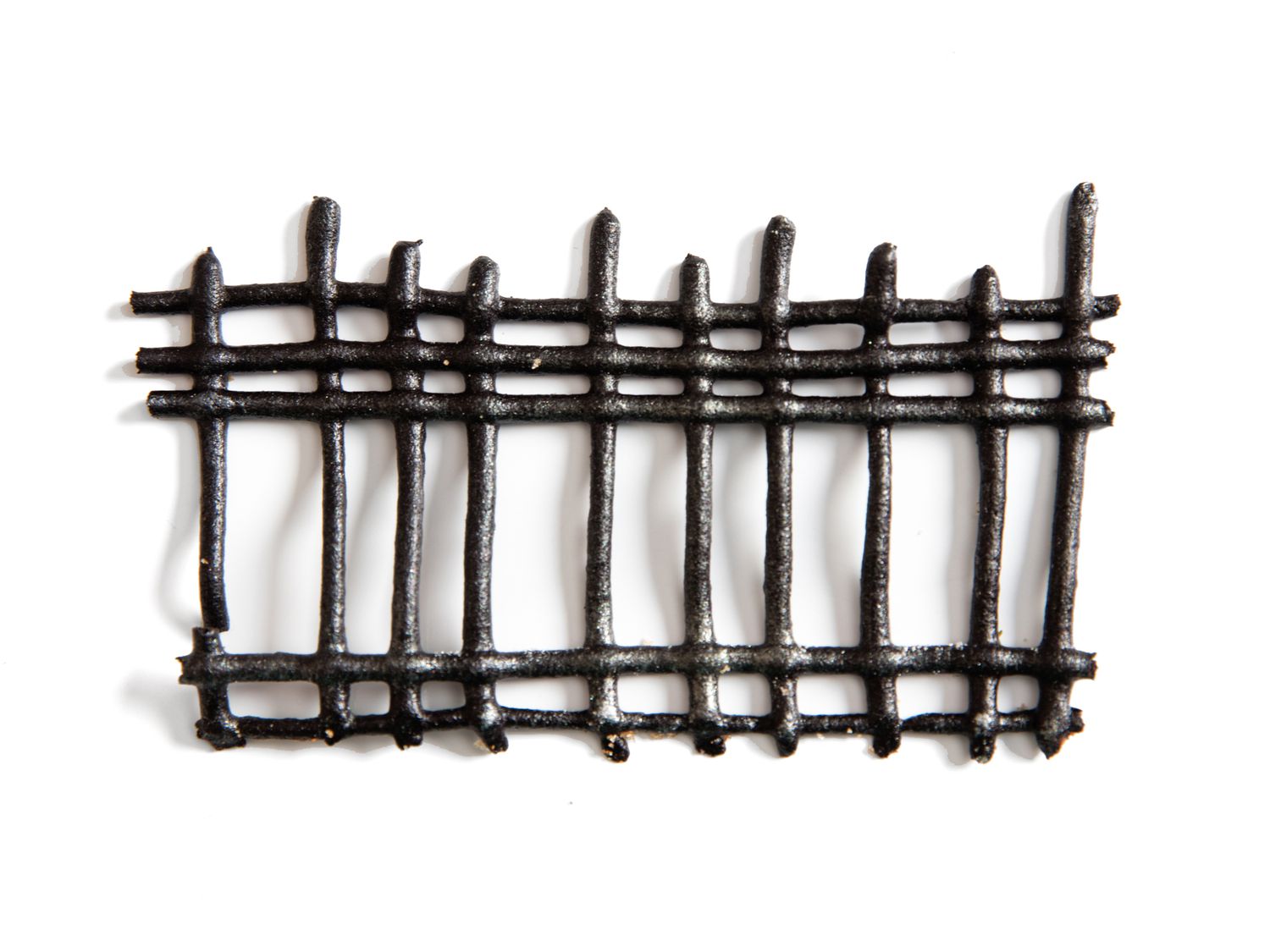A black, piped-out gate for a gingerbread house's fence, made from gingerbread paste.