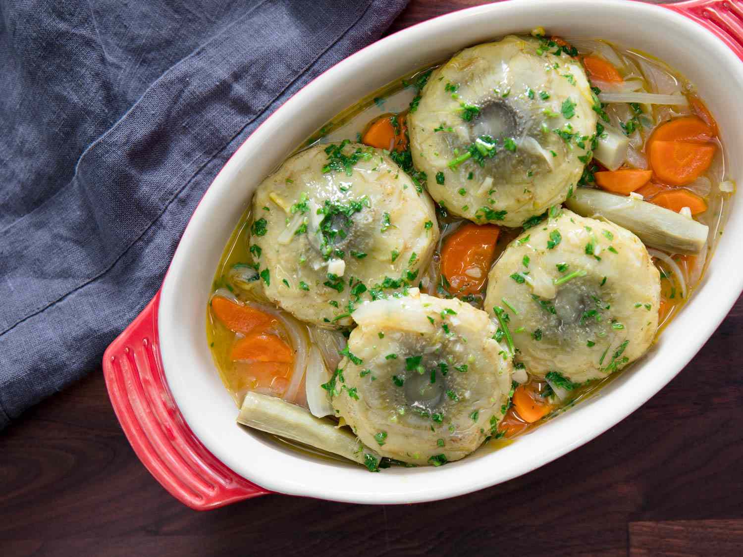 Overhead view of Artichokes à la Barigoule, served in a enalemed oval casserole dish.