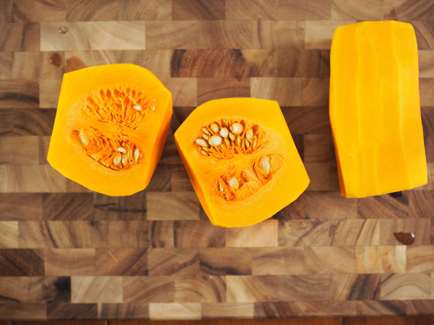 A butternut squash, cut in half, on a cutting board.