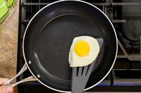 A fried egg on a spatula in a Kyocera ceramic frying pan