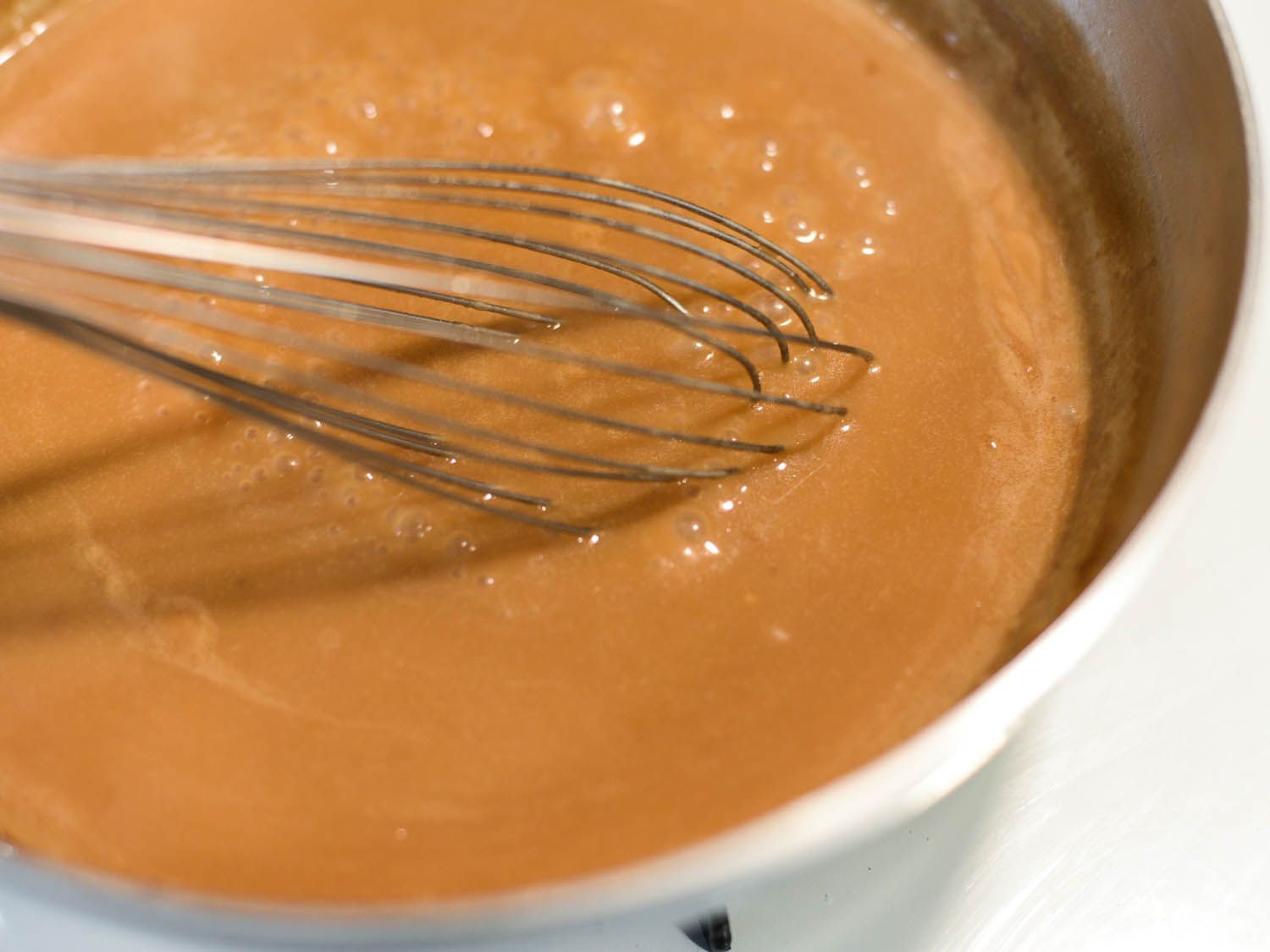 Whisking gravy for poutine in a saucepan. 