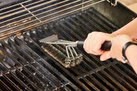 A person cleans the grill on the Weber Spirit EX-325s Smart Grill