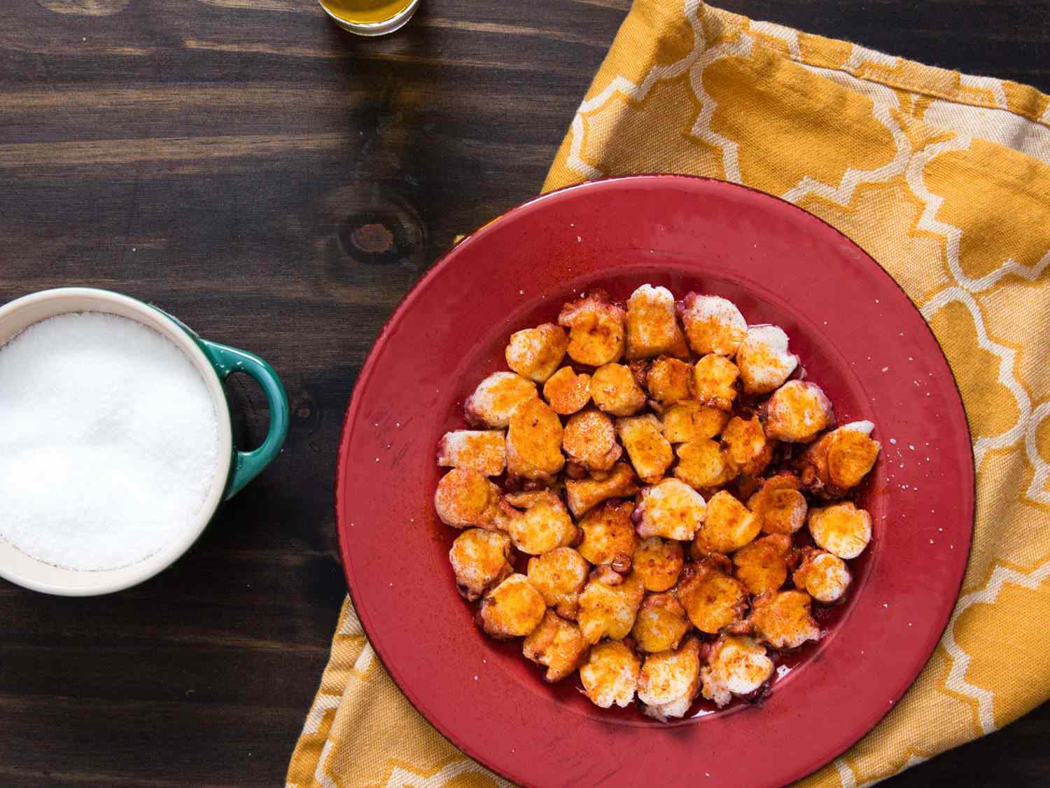 A plate of Galician pulpo gallego: tender cross-sections of boiled octopus tentacles seasoned with smoked paprika, salt, and olive oil.