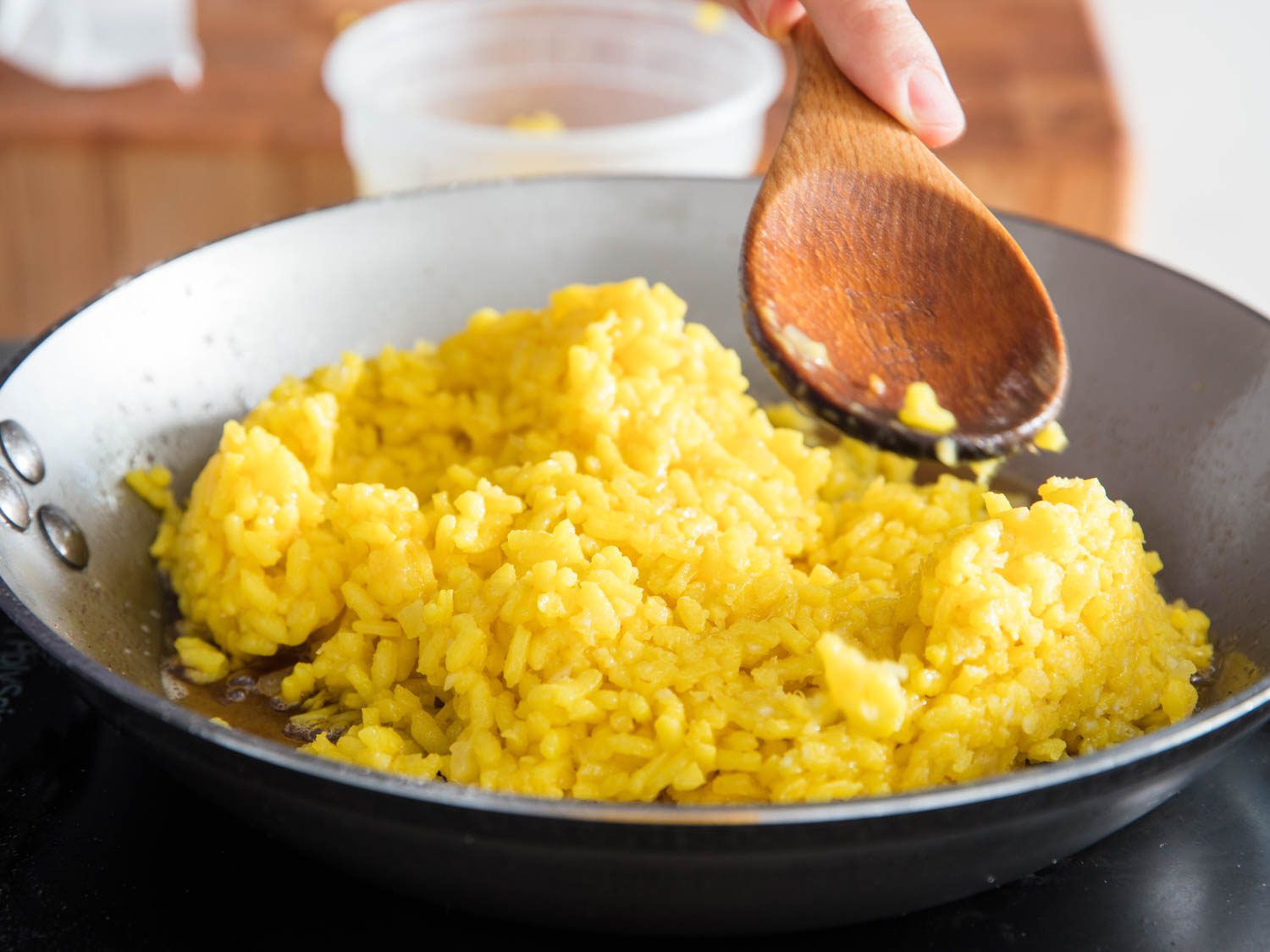Patting down saffron-hued risotto alla milanese in a carbon steel skillet.