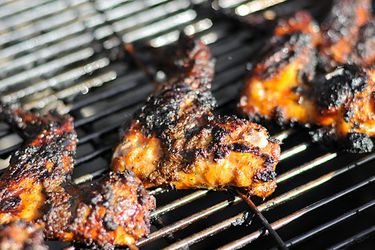 Jerk chicken wings cooking on a grill. 