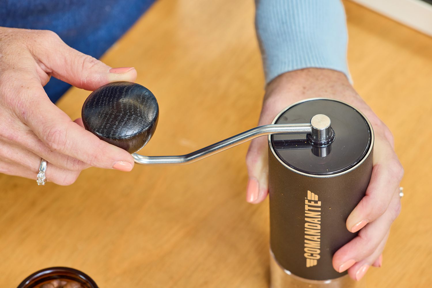 A person turns the crank on the top of the Comandante C40 Nitro Blade Grinder