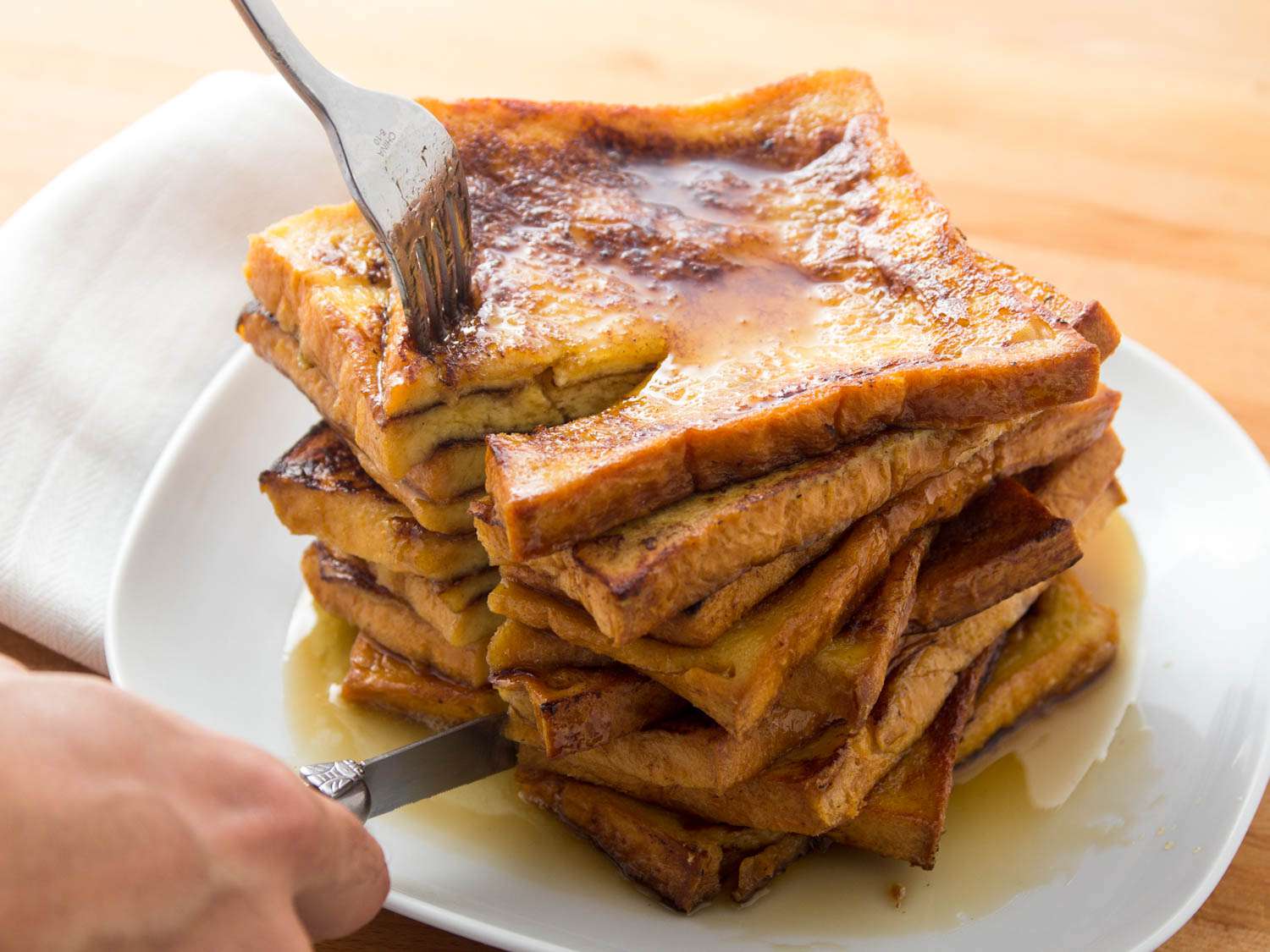 Slicing into a stack of French toast.