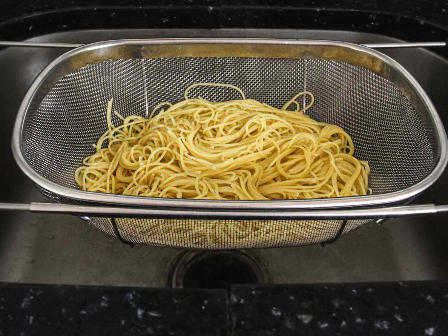 An over-the-sink colander with pasta in it