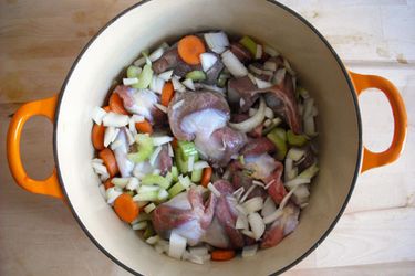 Turkey gizzards in a Dutch oven with chopped vegetables.