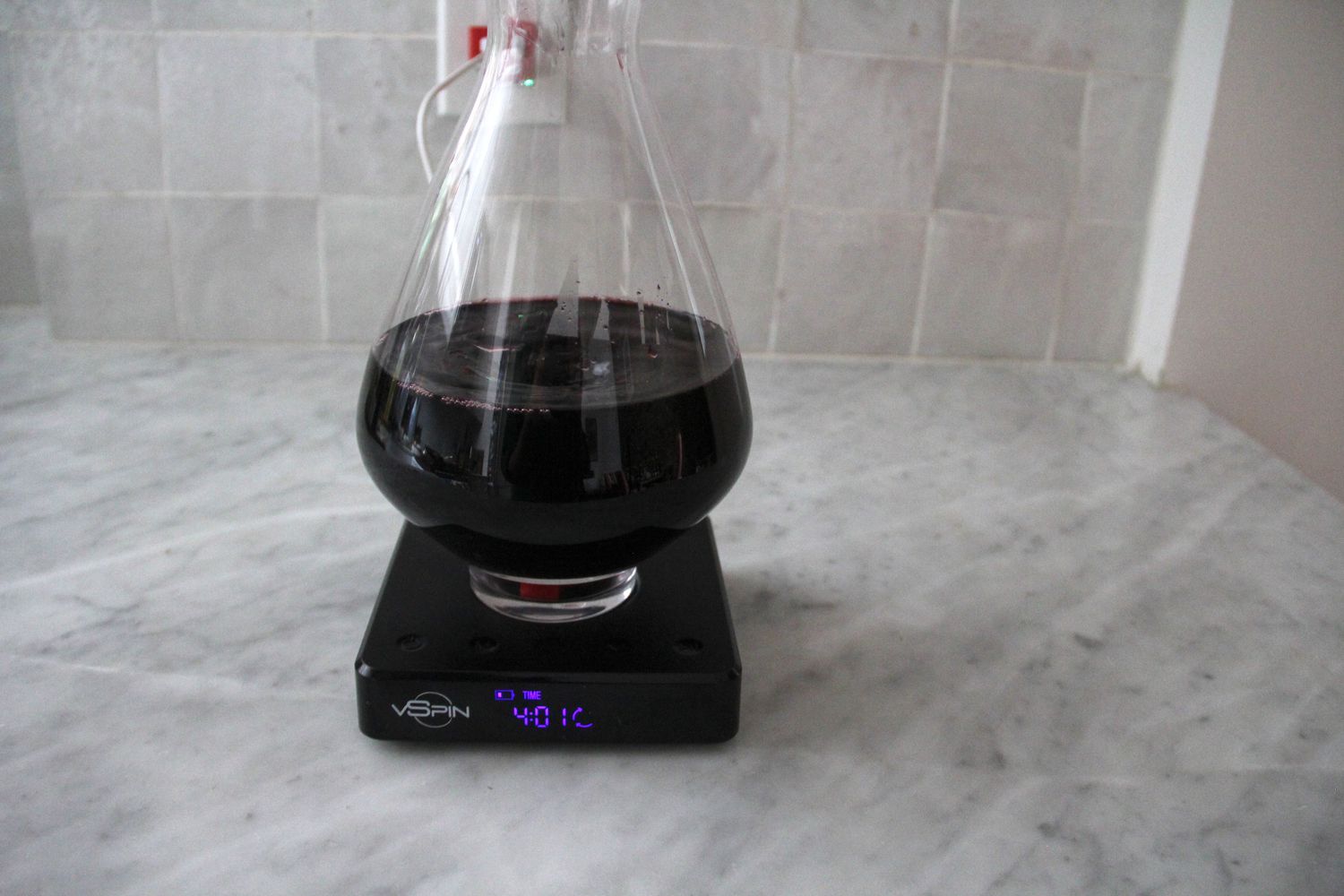 Red wine being decanted in the Vspin electric wine decanter on a marble counter