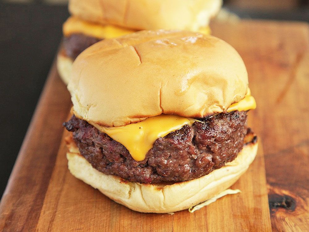 Homemade bison cheeseburgers on a wooden cutting board