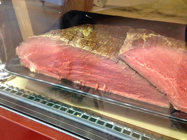 Roast beef in a deli case, ready to be sliced.