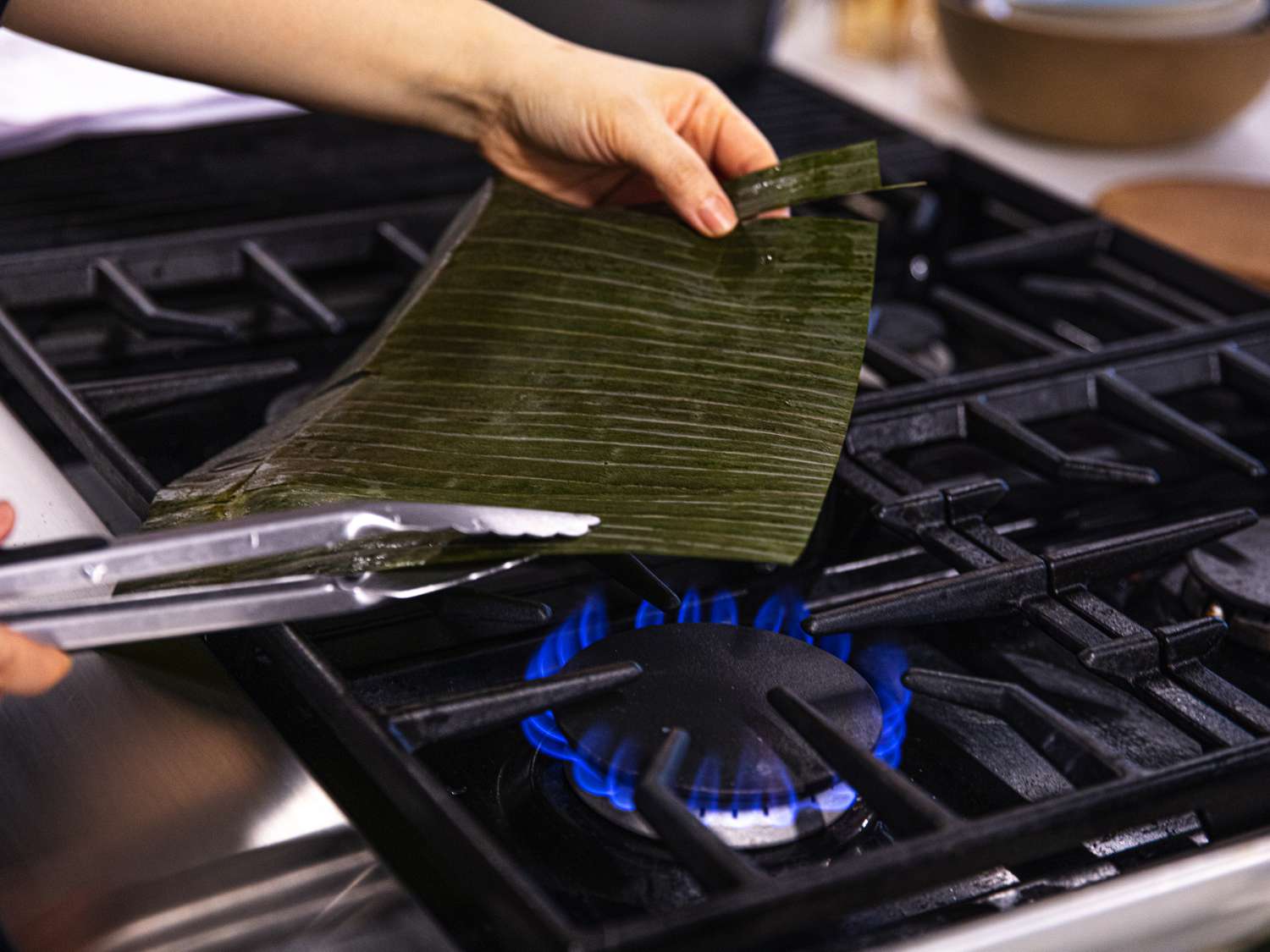 Side angle view of holding a banana leaf over the flame