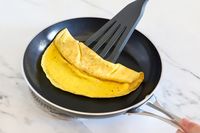 An omelet being folded in a Kyocera nonstick ceramic skillet with a spatula