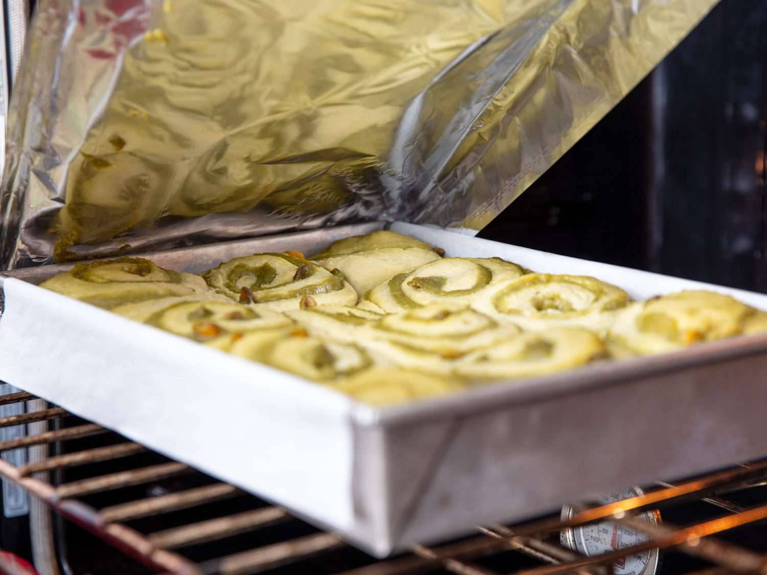 Removing the foil on pale and puffy, semi-baked pistachio buns.
