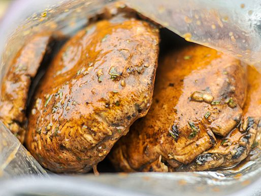 Closeup of the mushroom caps coated in marinade, nestled in a ziptop bag.