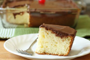 Profile view of a slice of gluten-free yellow cake with chicolate frosting.