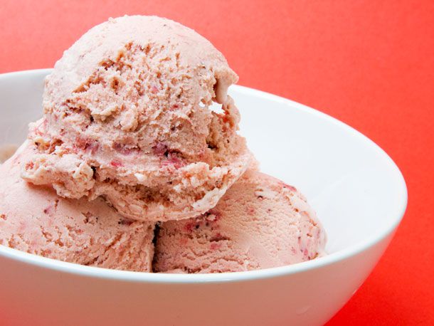Closeup of a triple scoop of Strawberry Balsamic Ice Cream, served in a small white bowl.