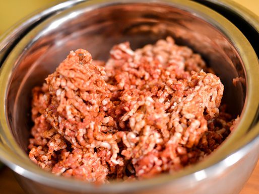 Uncooked raw lamb sitting in a silver bowl.