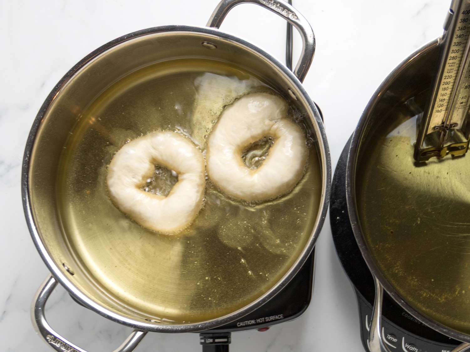 Donuts frying in oil in a pot on a stove, cooking stage shown