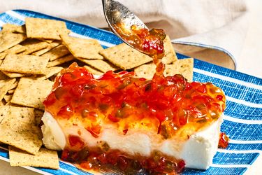 Cream cheese topped with pepper jelly, served on a plate with crackers
