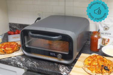 Compact pizza oven on a kitchen counter with freshly baked pizzas nearby