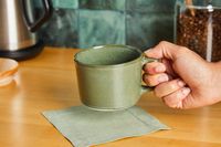 A person holding onto a Haand coffee mug.