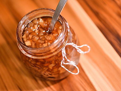 An open jar of pear and ginger preserves with a spoon in it.