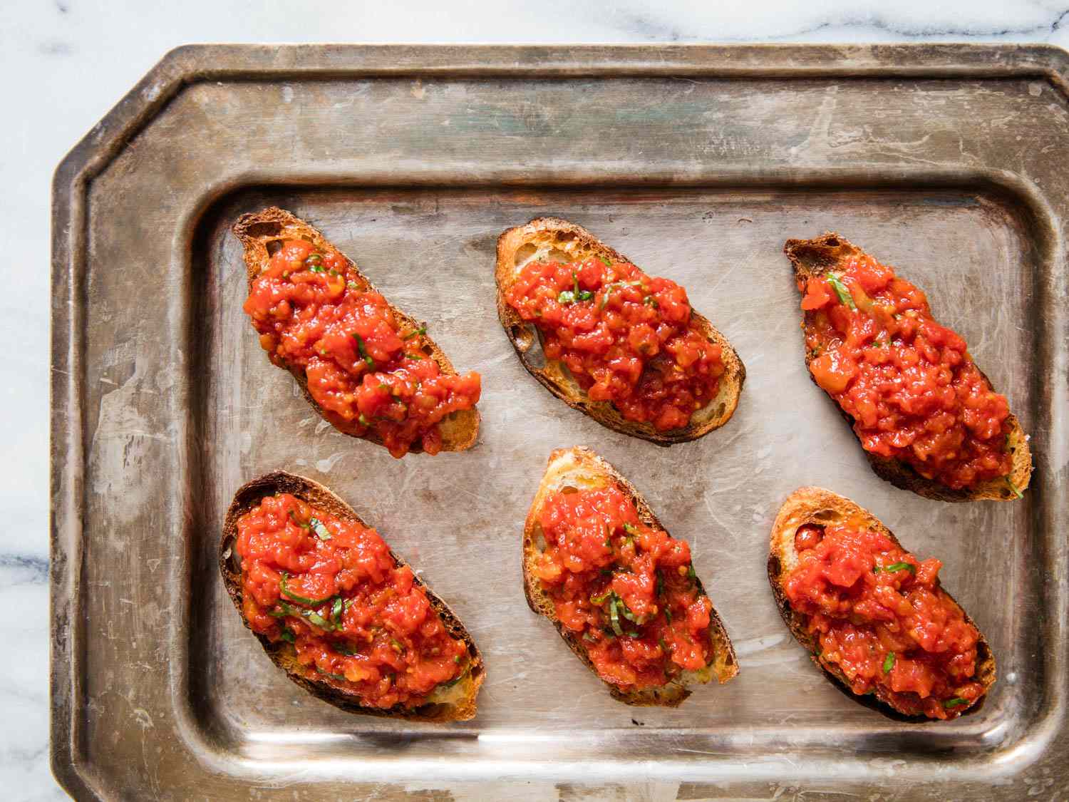 Overhead view of the finished brushetta arranged on a patinaed serving platter.