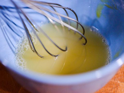 Whisking vinegar and seasoning ingredients in a small bowl