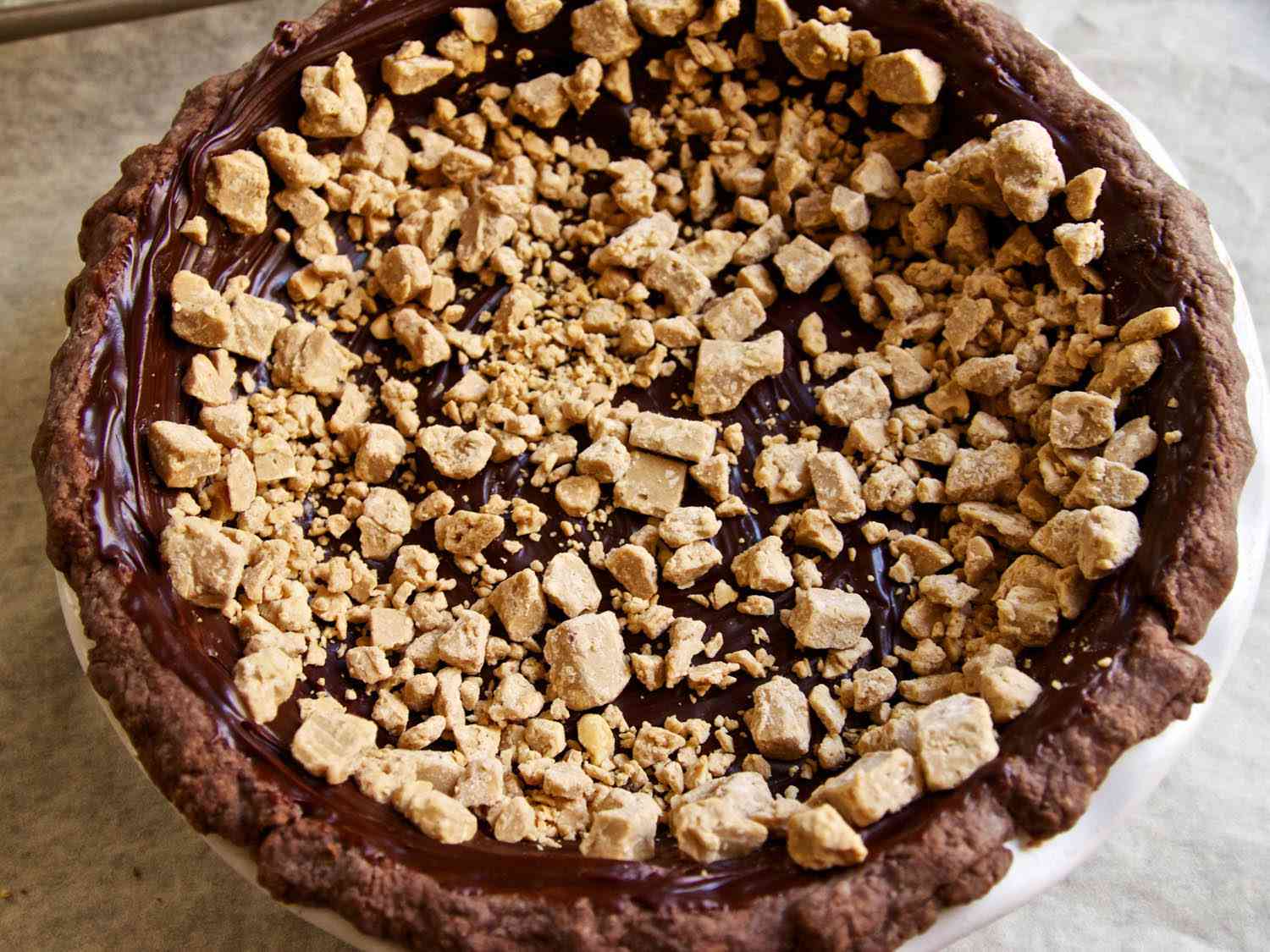 Adding a layer of frozen peanut butter ganache chunks over the chocolate caramel.