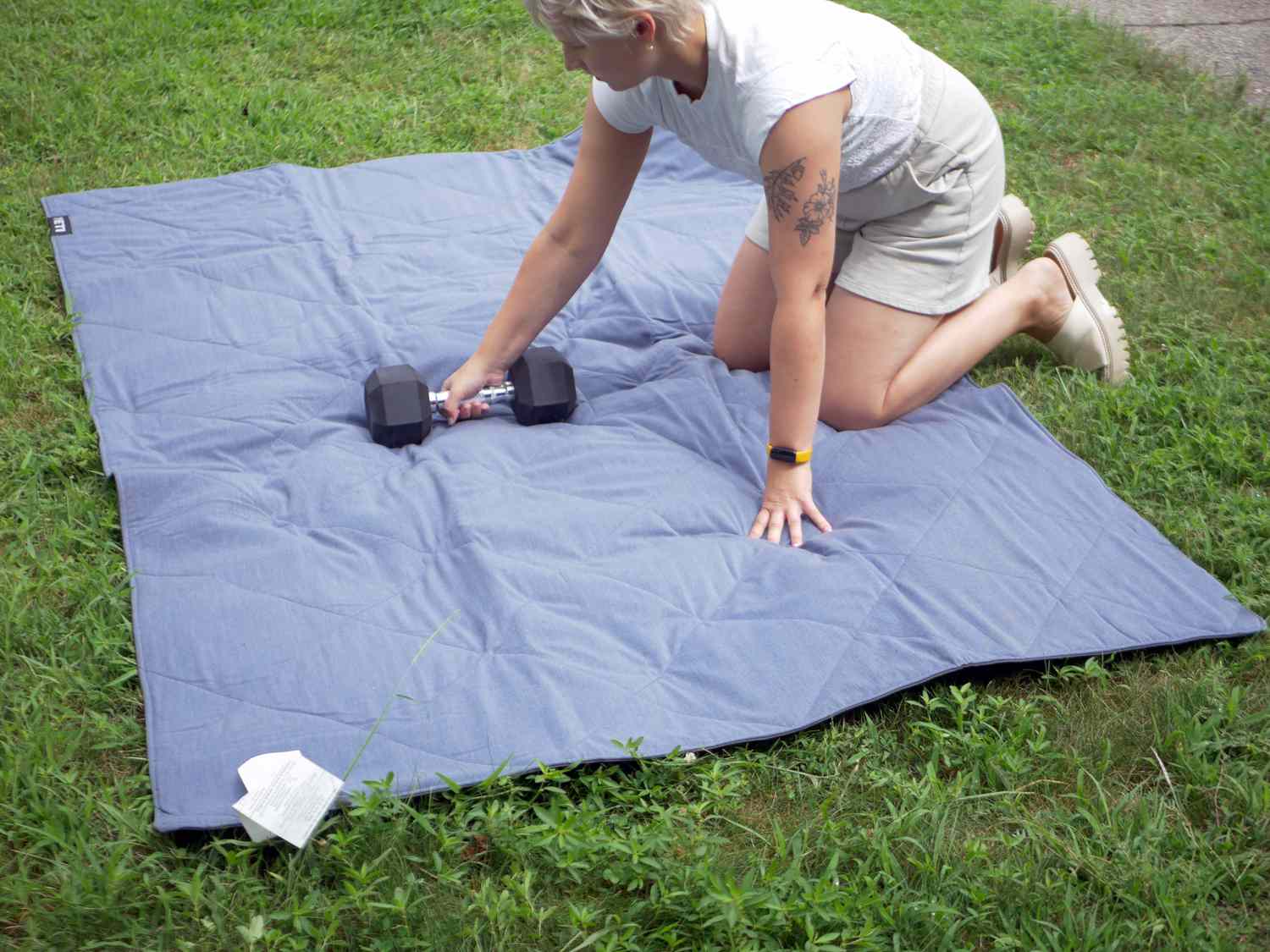 person placing weight on yeti blanket in yard