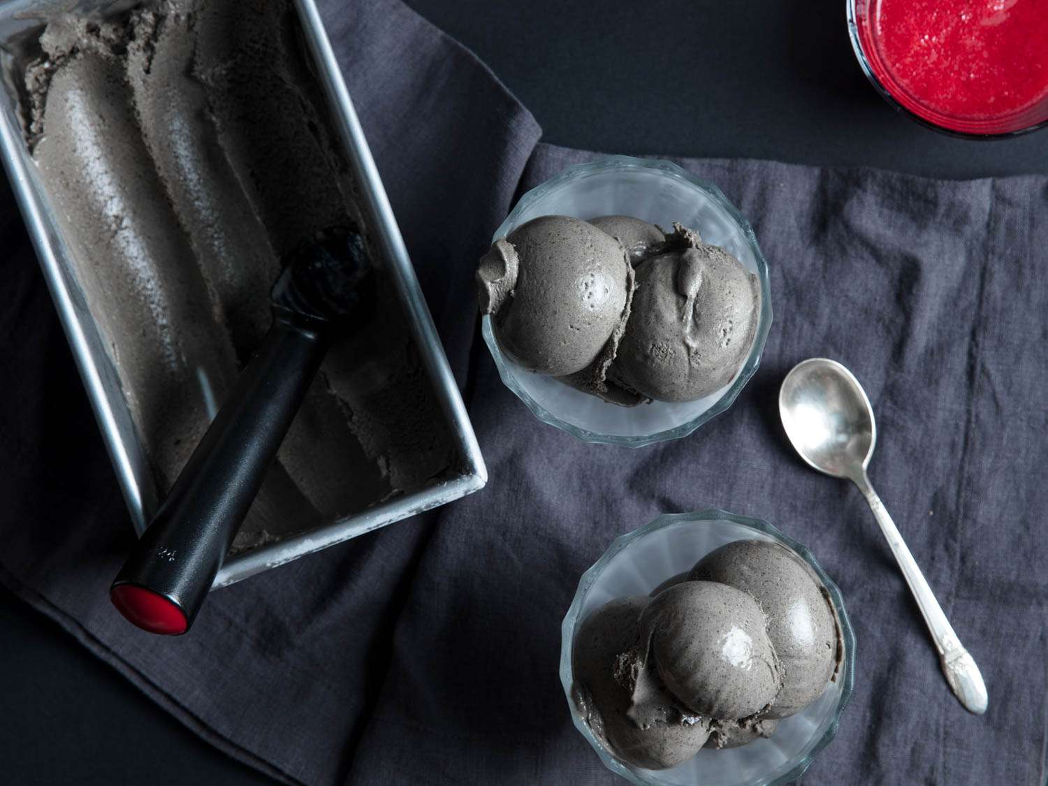 Overhead shot of black sesame ice cream scooped into serving bowls and the container it's from. 