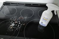 A stovetop with cleaning product applied a spray bottle labeled ATTITUDE placed on the surface