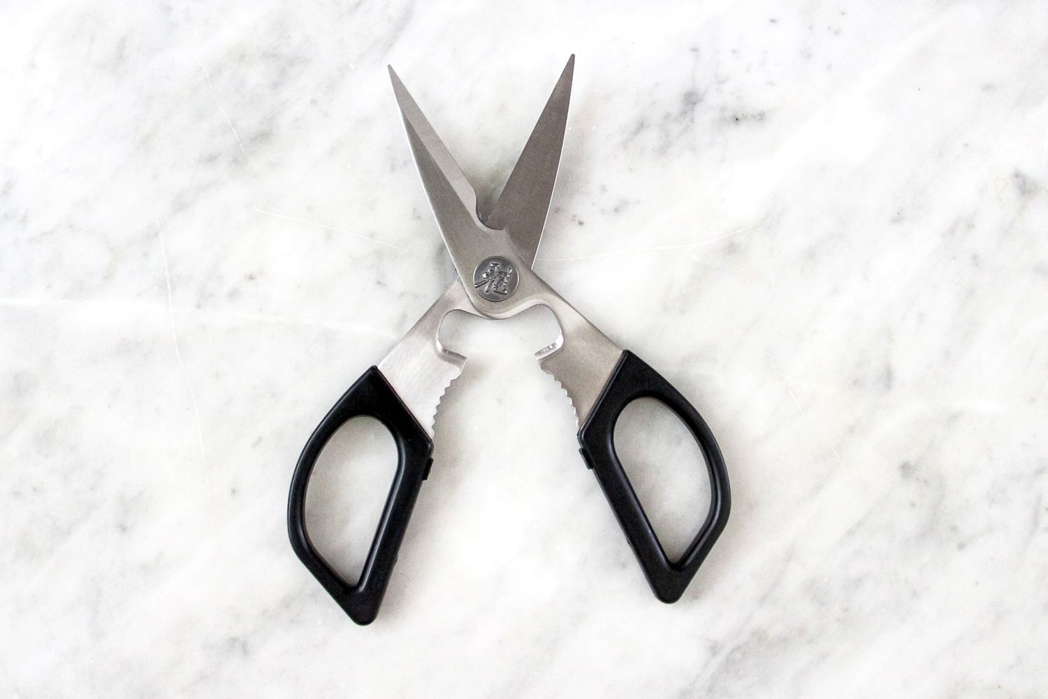 Kitchen shears with black handles on a marble surface