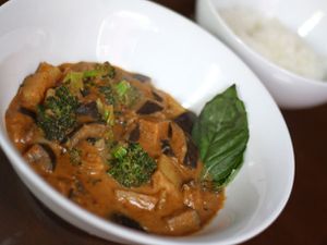 Closeup of Massaman Curry with Eggplant and Broccoli, served in smsll white bowl.