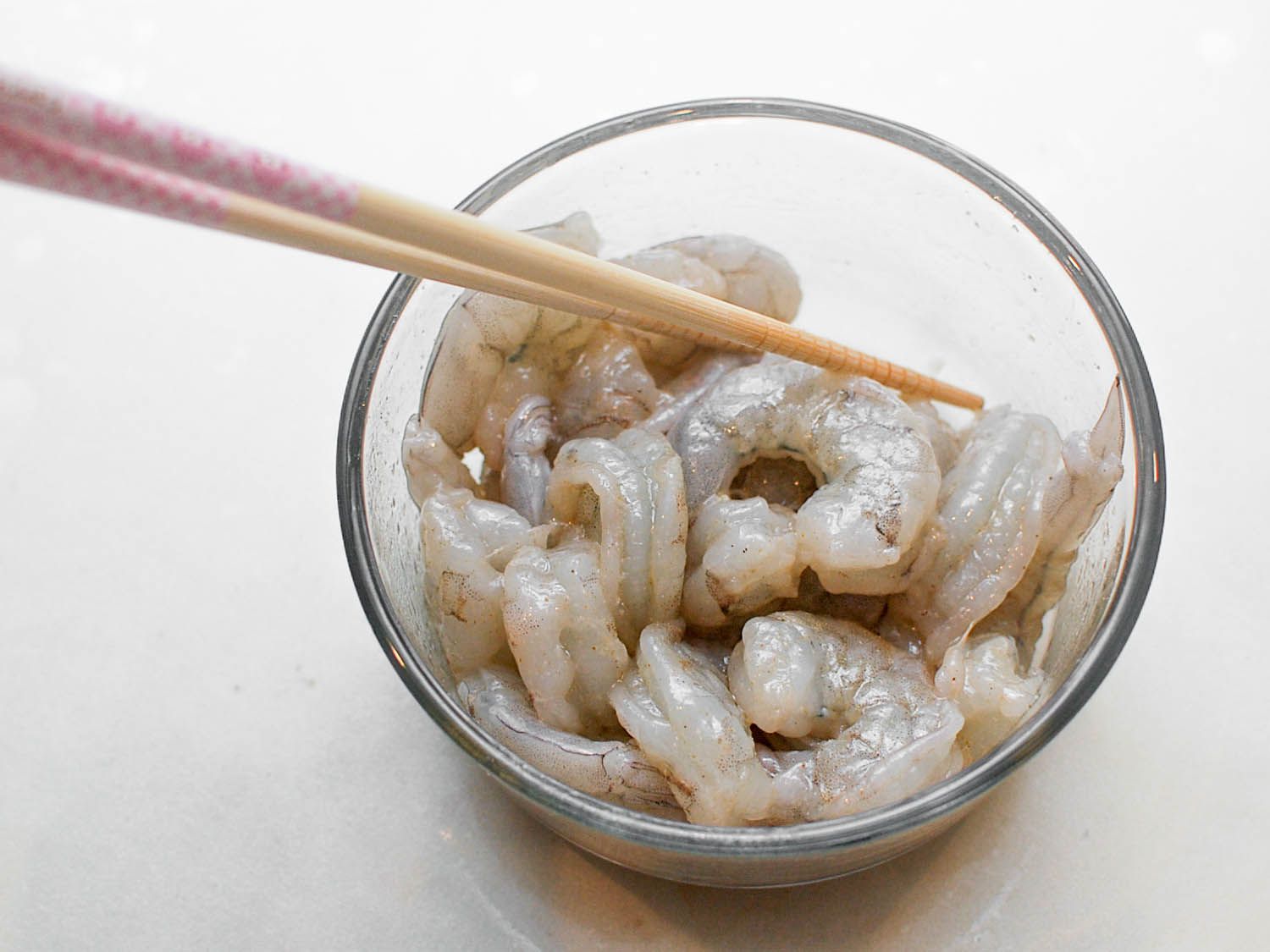 The brined shrimp are mixed in a small bowl with oil, salt, and pepper.