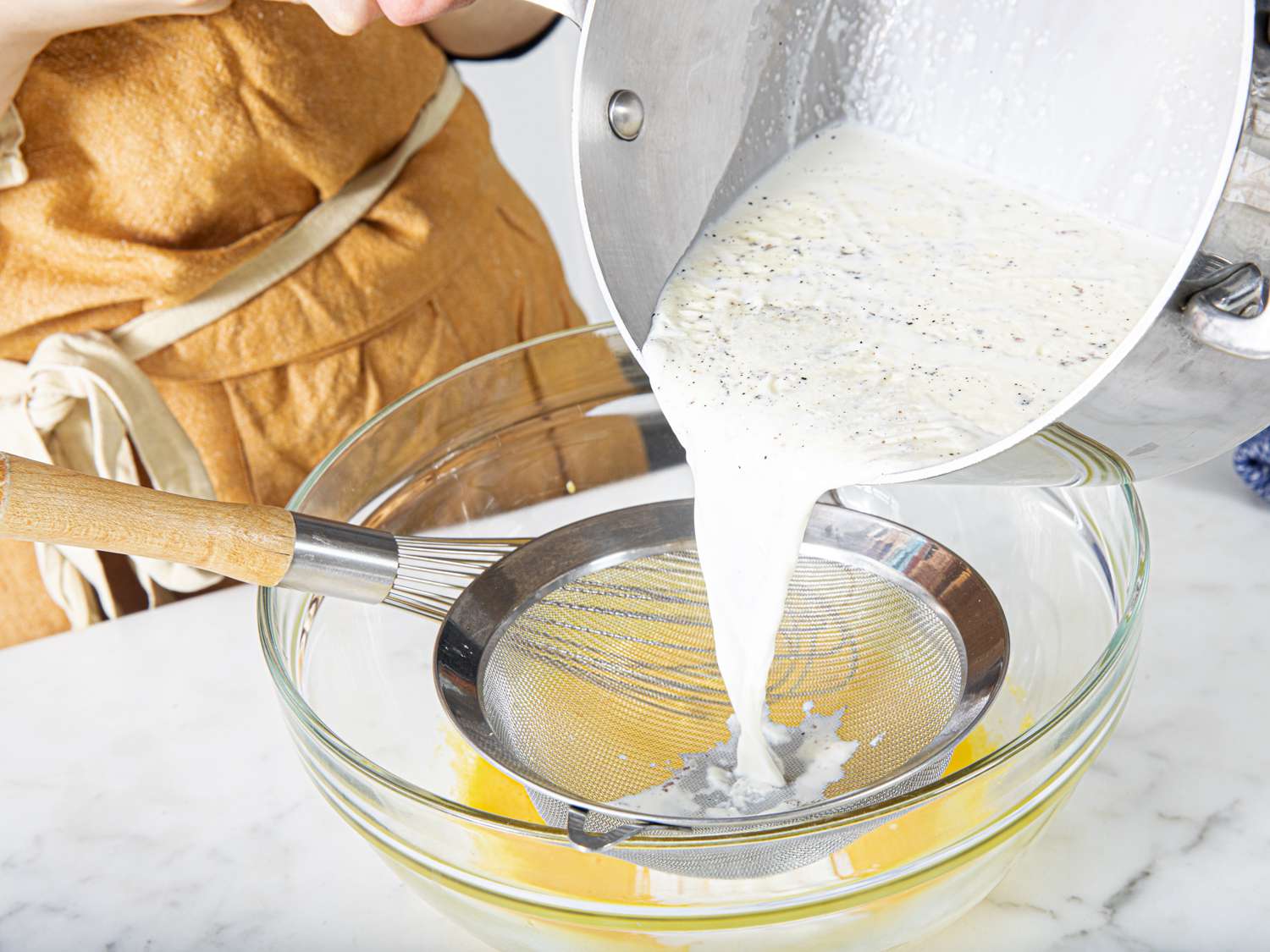 Side angle view of pouring milk mixture into bowl with eggs