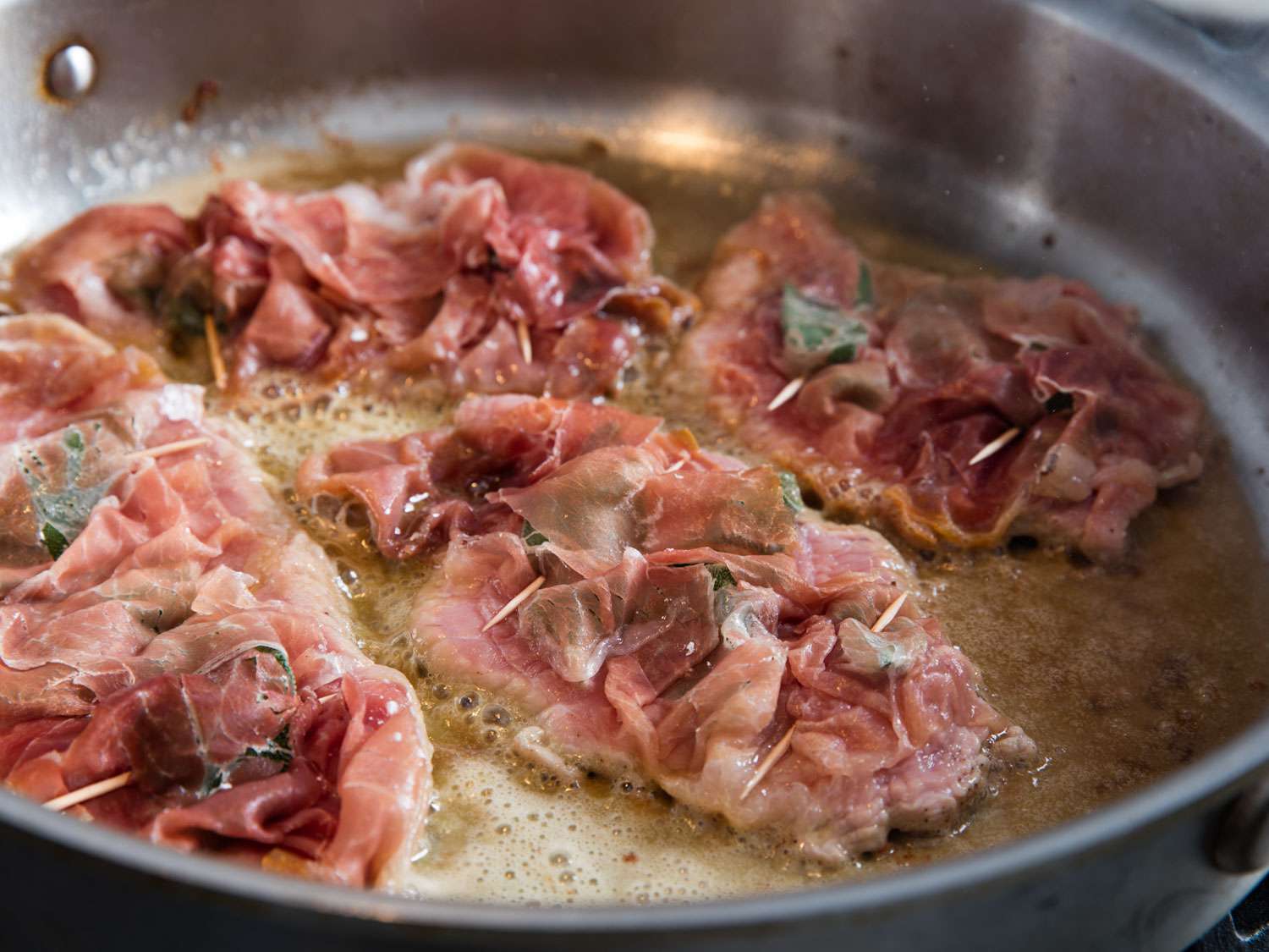Pan-frying pieces of saltimbocca in skillet.