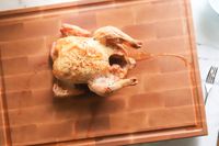 A roasted chicken on a carving board