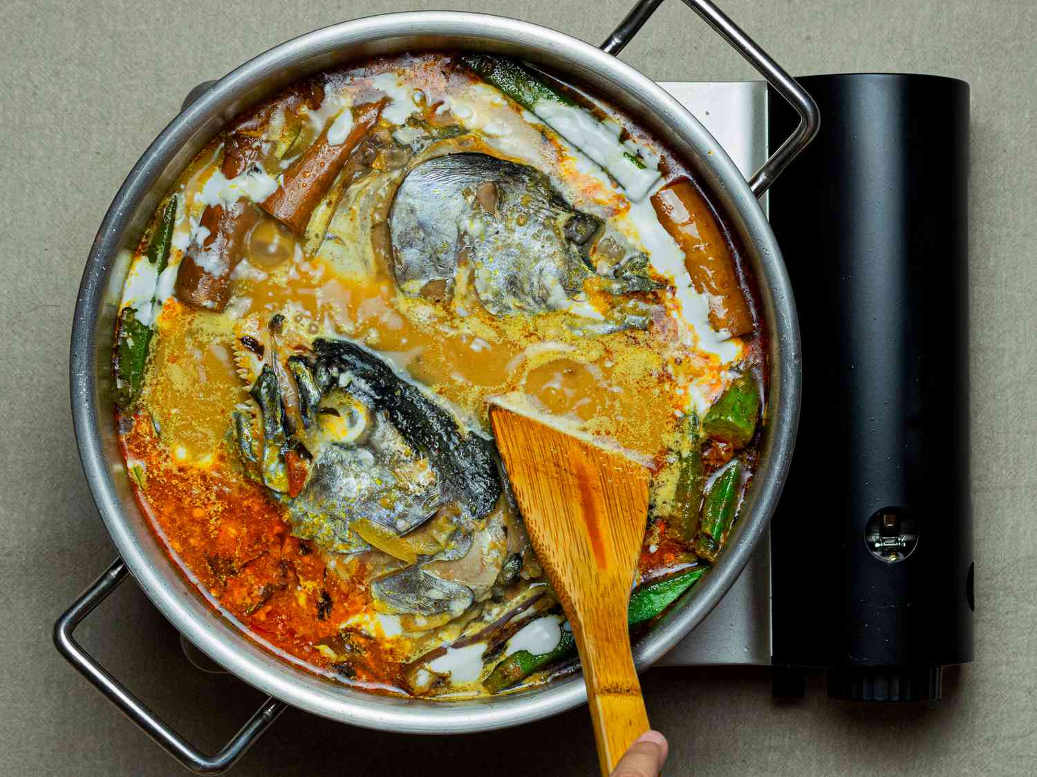 Overhead view of fish head curry cooking after coconut milk has been added