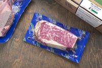 A packaged portion of marbled steak on a wooden surface