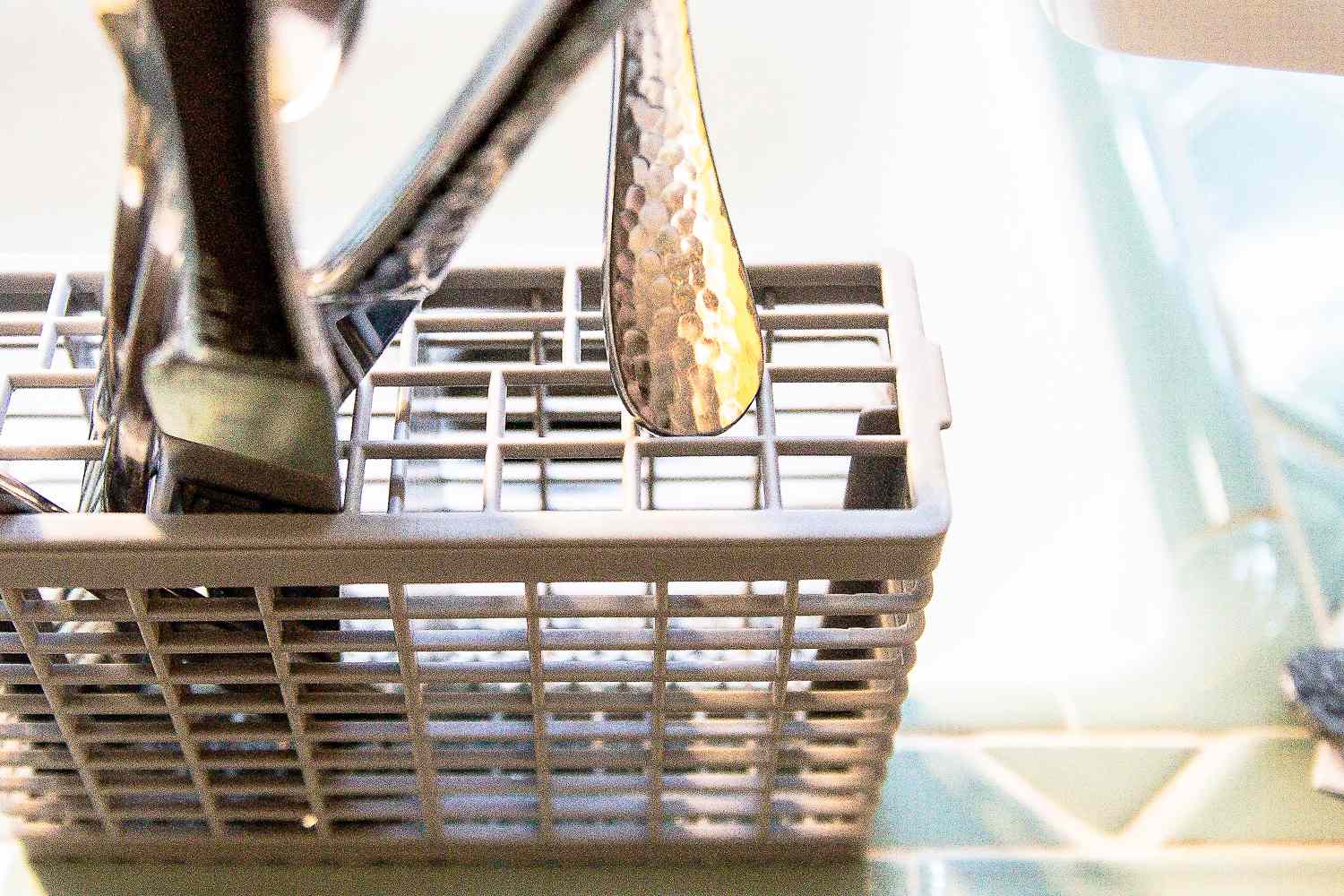 A person adding utensils to the utensil caddy of the Hermitlux countertop dishwasher.