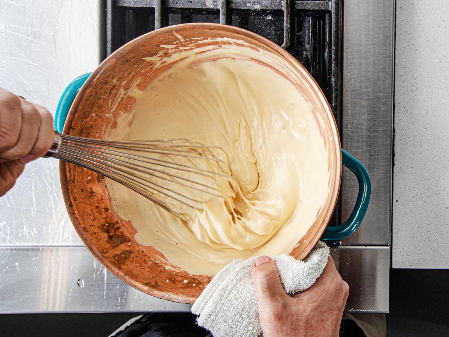 A hand whisking zabaglione in a copper bowl on the stove.