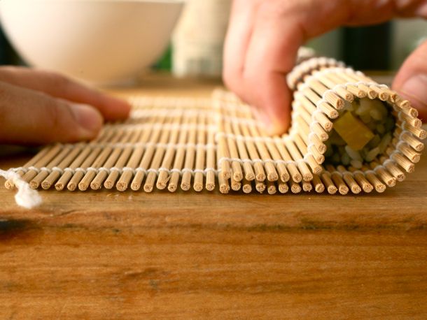 A sushi mat being used to roll sushi.