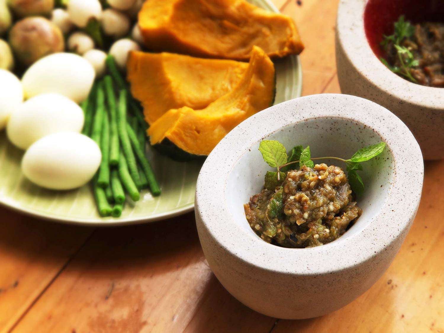 A dish of nam phrig noom (Northern Thai roasted-chili dip) next to assorted items for dipping
