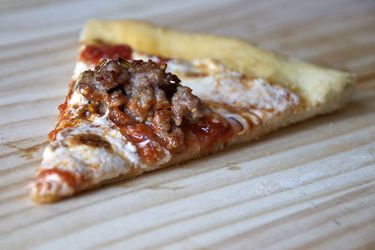 Closeup of a slice of pizza topped with Pizza a Casa's spicy salsiccia.