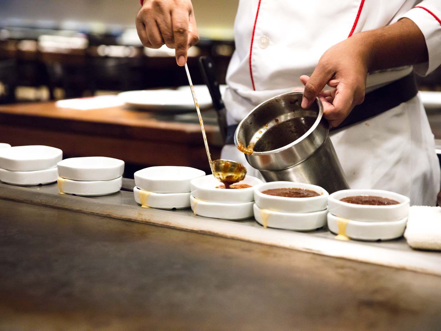A Benihana cook portioning out dipping sauces.