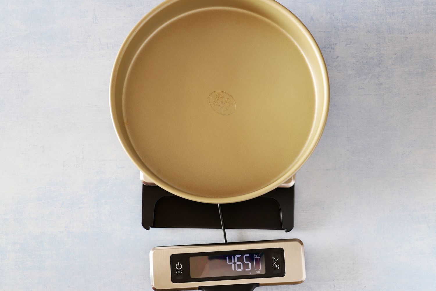 The OXO kitchen scale with an empty cake pan on it.